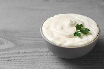 Tasty mayonnaise and parsley in bowl on gray wooden table, closeup. Space for text