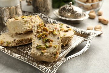 Tasty pistachio halva on light grey table, closeup