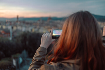 back view of female take a photo of golden sunset over Palazzo Vecchio and Cathedral of Santa Maria del Fiore (Duomo), Florence, Italy. High quality photo - obrazy, fototapety, plakaty