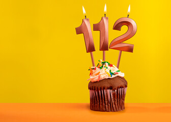 Candle with flame number 112 - Birthday card on yellow background