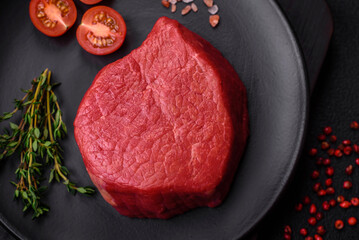 Fresh juicy raw filet mignon with salt, spices and herbs