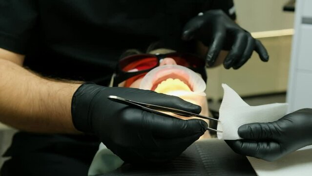 A dentist takes out pieces of a dental cast of a woman patient using medical tweezers.