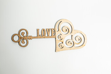 Wooden key and heart on a white background