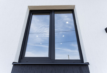 Plastic window in the house, gray double-glazed window view from the street, exterior wall of the house with a window.