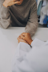 Doctor and patient sitting near each other at the table in clinic office. The focus is on female...