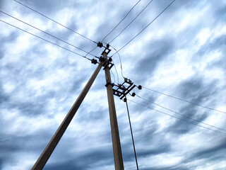 Old power poles and the sky with clouds in the background. Electric lines, towers, wires in the landscape