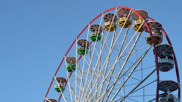 Bayonne Ferris wheel, in France, spinning around illuminated by the sun during a day with a clear and homogeneous sky, with copy space in the upper left space