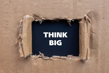 Think big lettering on ripped cardboard paper with black background. Conceptual business photo. Top...