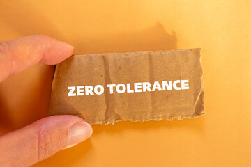 Zero tolerance lettering on ripped cardboard paper with orange background. Conceptual photo. Top...