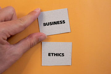 Business ethics lettering on ripped paper pieces with orange background. Conceptual business photo....