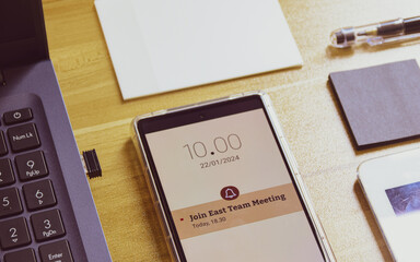 Join East team meeting mobile phone reminder on display. Close up image, selective focus.	