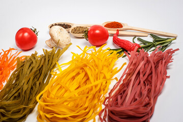 Raw pasta with spices and different vegetables on a white background