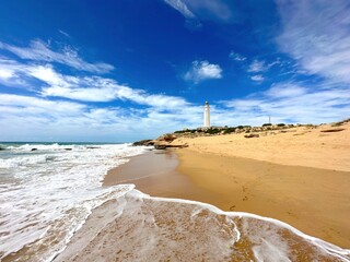 Faro de Trafalgar, vista desde la playa hasta el faro en un promontorio arenoso con dunas entre Los...