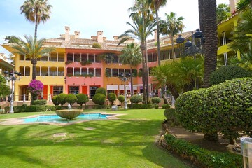 public green courtyard with palm trees, fountain colorful houses in Sotogrande at the Mediterranean...