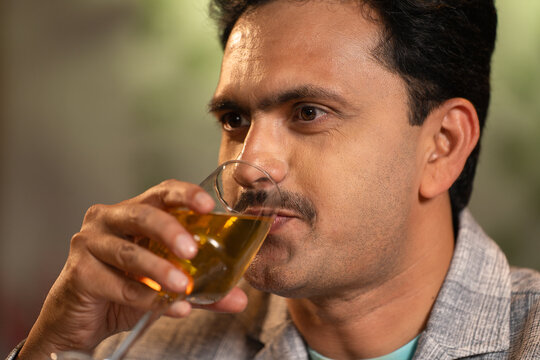 Close up shot of middle aged Indian man drinking wine at weekend night party at restaurant - concept of luxury lifestyles, refreshment and relaxation