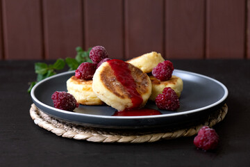 Cheese fritters Syrniki with raspberries and honey on a plate. Ukrainian cuisine food. 