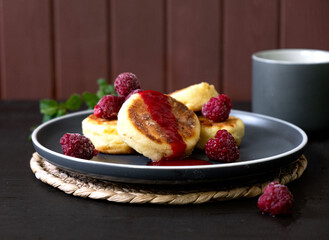 Cheese fritters Syrniki with raspberries and honey on a plate. Ukrainian cuisine food. 