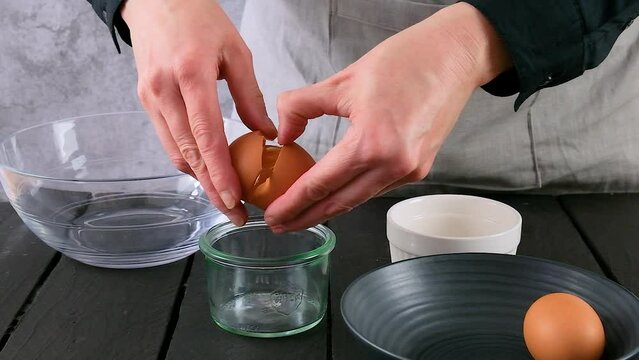 Shot of breaking eggs to separate whites from yolks. Pie maker breaking eggs in a bakery. 