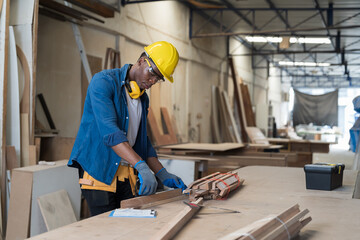 Male carpenter working in wood processing plants. Black male carpenter working at wood workshop. Concept of wood industrial factory - obrazy, fototapety, plakaty