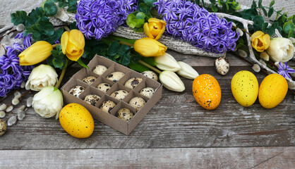 Easter eggs with tulips and hyacinths on a wooden background.