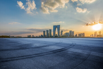 Empty asphalt road and city buildings skyline at sunset in Suzhou