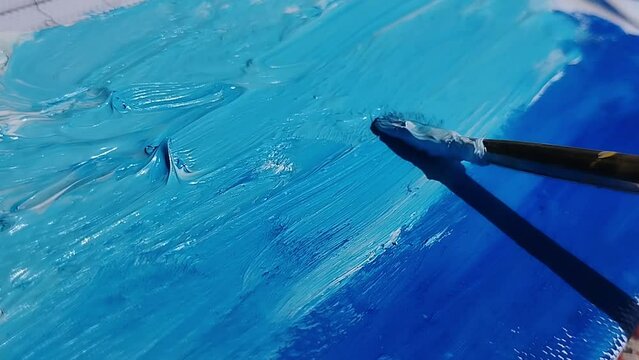 Painting a blue background with oil paints on canvas. Mixing the colors of the sea and sky. Stock video of the artist's work in full HD.