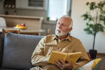 Senior men enjoying time at home by reading his favorite book.