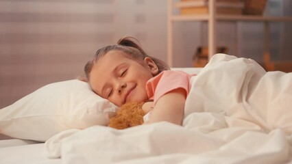 Adorable young girl asleep, embracing teddy bear in cozy bed, peaceful rest