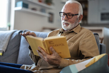 Caucasian mature senior old elderly man with grey hair reading book at home, active seniors....