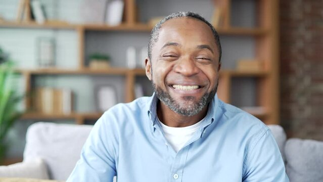 Webcam View. Smiling Mature African American Male Talking On Video Call Looking At Camera While Sitting On Sofa In Living Room At Home Office. Happy Senior Black Man Has A Remote Meeting With A Friend