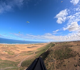 beauty of paragliding flying over scenic seaside landscape,sand dunes and mountain terrain,aerial...