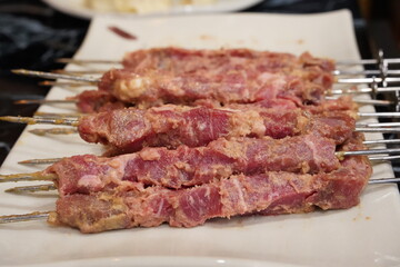 Raw, uncooked lamb skewers are served.