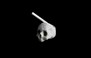 Skull stucco ashtray with a cigarette isolated on black background
