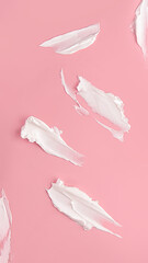 Diferentes texturas de una crema de cosmética sobre fondo rosa.