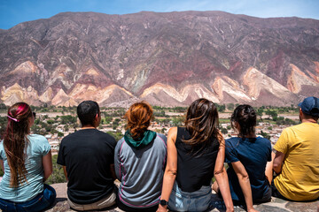 Grupo de amigos sentados en el mirador de Maimará admirando los cerros coloridos - obrazy, fototapety, plakaty