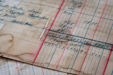 Closeup of vintage grungy, ledger paper with handwriting in ink and coffee stains. 
