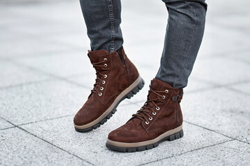 A pair of dark brown leather boots and grey denim jeans make a stylish statement in this urban fashion photo.