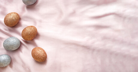 Golden and silver glitter Easter eggs on a pink and coral background. Festive Easter background. Easter concept. Handmade decorated Easter eggs. Greeting card. Space for text. Banner