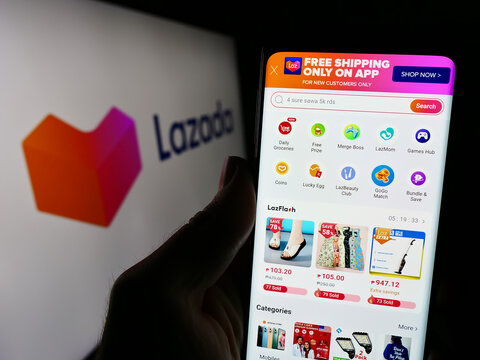 Stuttgart, Germany - 12-20-2023: Person holding cellphone with webpage of Asian e-commerce company Lazada Group in front of business logo. Focus on center of phone display.