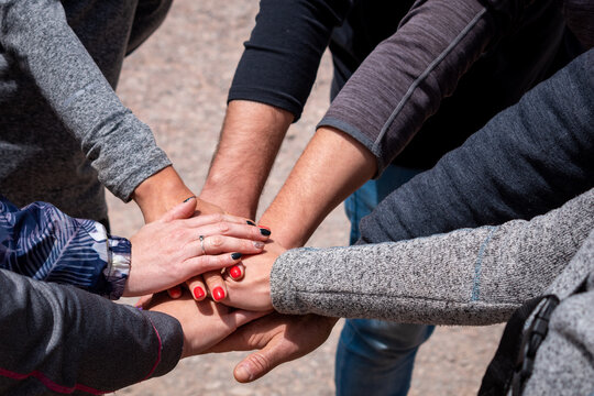 Grupo de compa&ntilde;eros agrupando sus manos en se&ntilde;al de trabajo de equipo