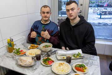 Stockholm, Sweden  Two young men eating falafel and hummus in a popular falafel restaurant in the Ragsved ethnic district.