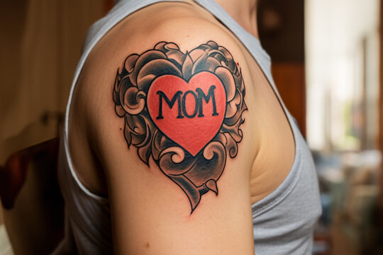 Red heart shaped tattoo with text 'MOM' on man's upper arm