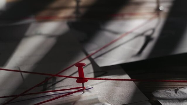 Close up shot of investigation board. Detective board with map of crime scene, pinned evidences and red thread connecting clues.