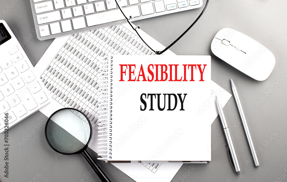 Poster feasibility study text on notepad on chart with keyboard and calculator on grey background