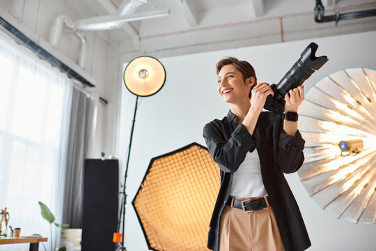 joyous female photographer in casual attire with camera in her hands smiling and looking away