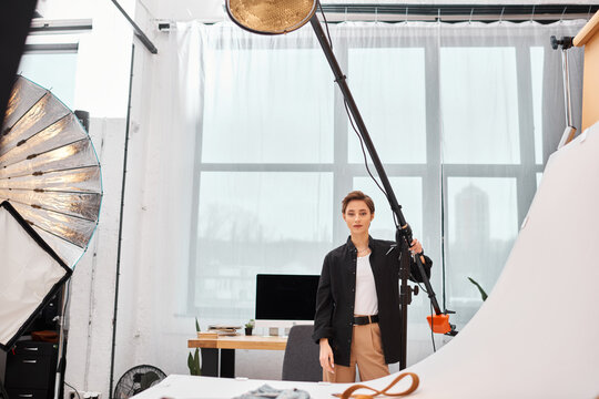 charming young female photographer in casual clothing working with her equipment at studio