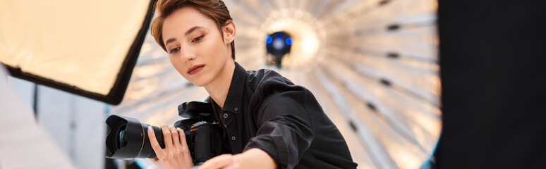 appealing focused female photographer holding camera and preparing to take photos in her studio