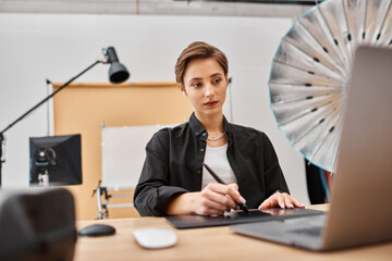 attractive professional female designer in casual attire working with her drawing tablet in studio