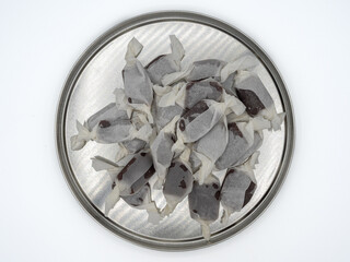 Top view of a silver plate with a pile of homemade fudge candies wrapped in paper, isolated on a...