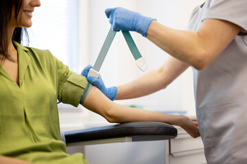 Nurse takes a venous blood test from the arm of a young woman in laboratory. Medical worker...